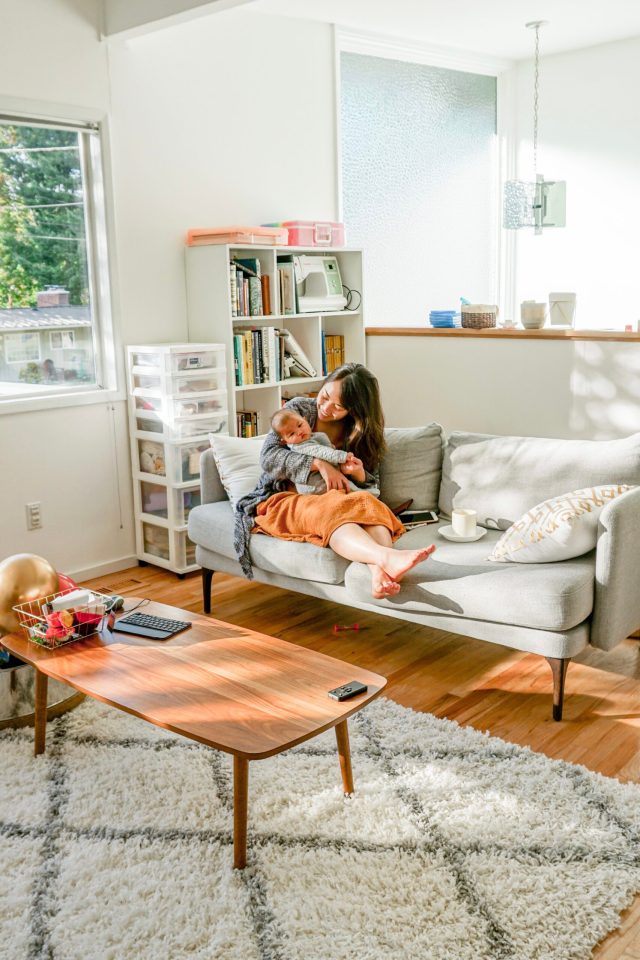 Mom and baby sitting on West Elm sofa in mid century modern living room