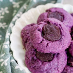 ube thumbprint cookies on a white plate with a green dish towel background