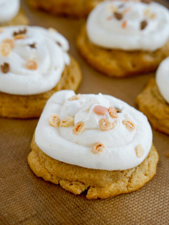 angled closeup of cakey pumpkin cookies with cream cheese frosting and Halloween sprinkles
