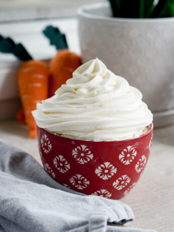 whipped cream cream cheese frosting in a red bowl with piped swirl on top