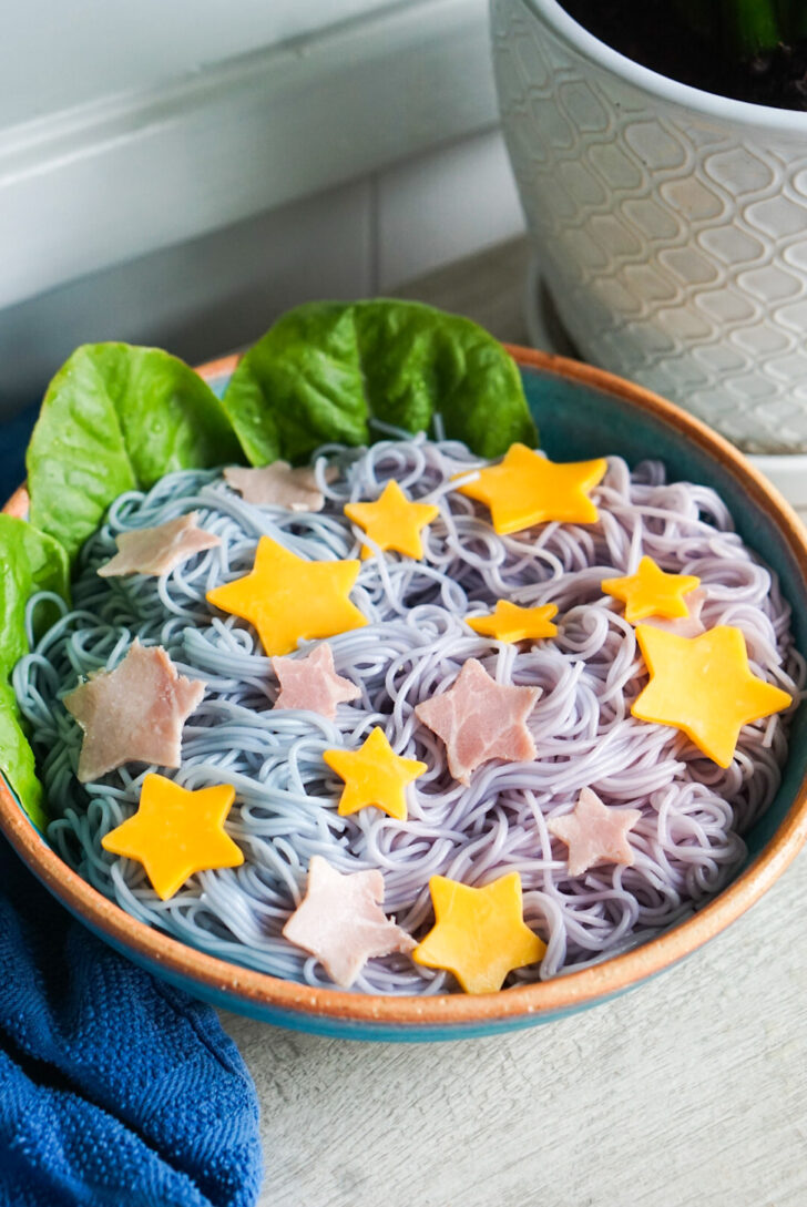 angled shot of tanabata somen in a serving dish with blue and purple noodles under pink and yellow stars