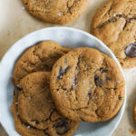 three kinako whole wheat chocolate chip cookies on round white ceramic plate on cookie sheet