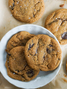 three kinako whole wheat chocolate chip cookies on round white ceramic plate on cookie sheet
