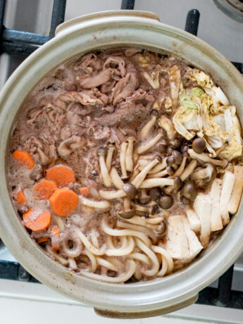 overhead shot of sukiyaki in a clay pot over stovetop