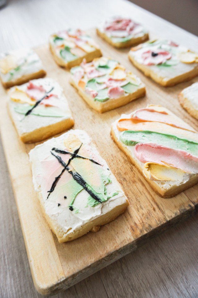 Rectangular cut out shortbread cookies with American buttercream frosting. The buttercream is spatula painted on in an abstract design.
