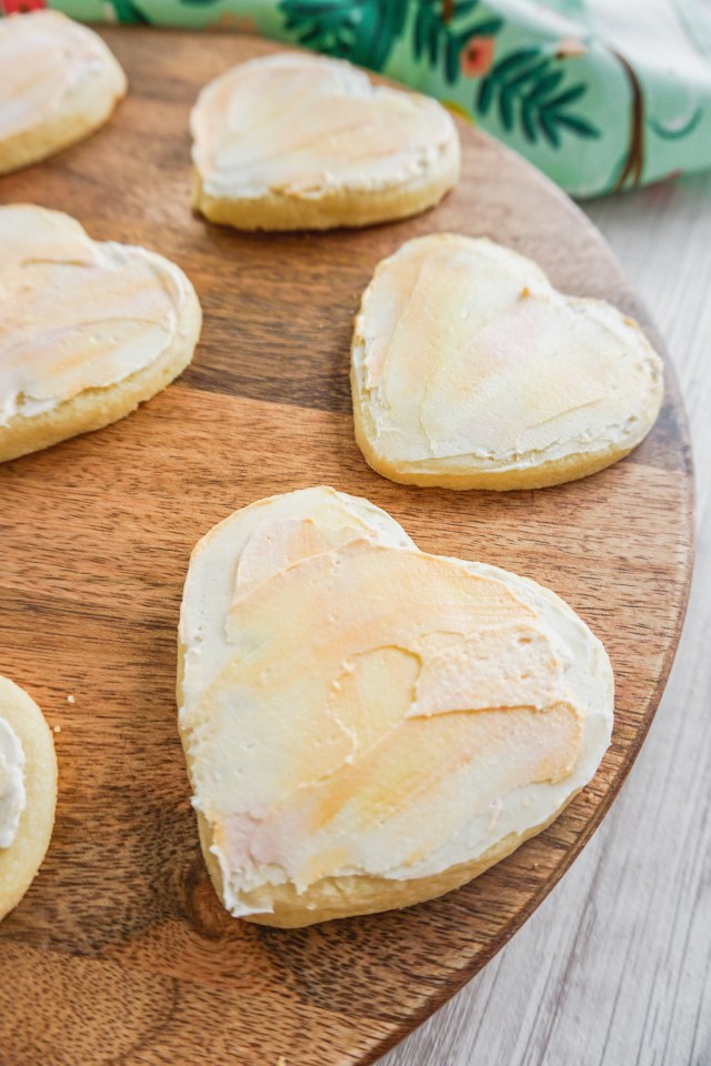 Heart shaped cut out shortbread cookies with American buttercream frosting. The buttercream has a watercolor painted effect.