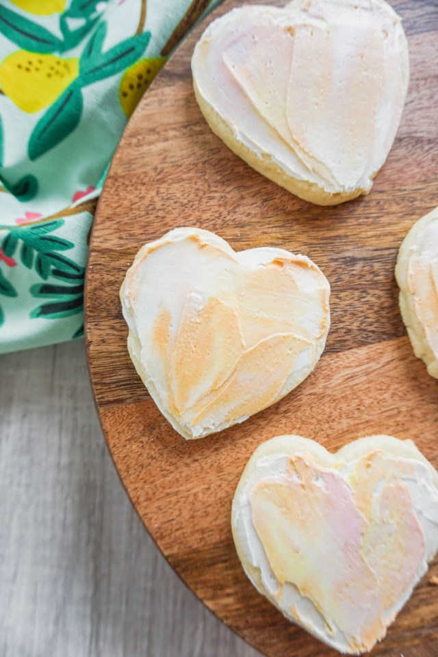 Heart shaped cut out shortbread cookies with American buttercream frosting. The buttercream has a watercolor painted effect.