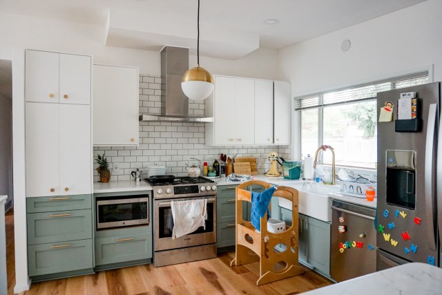 mid century modern kitchen renovation - two toned white and green cabinets, marble countertops, globe pendant light, gold hexagon knobs, and gold cabinet pulls
