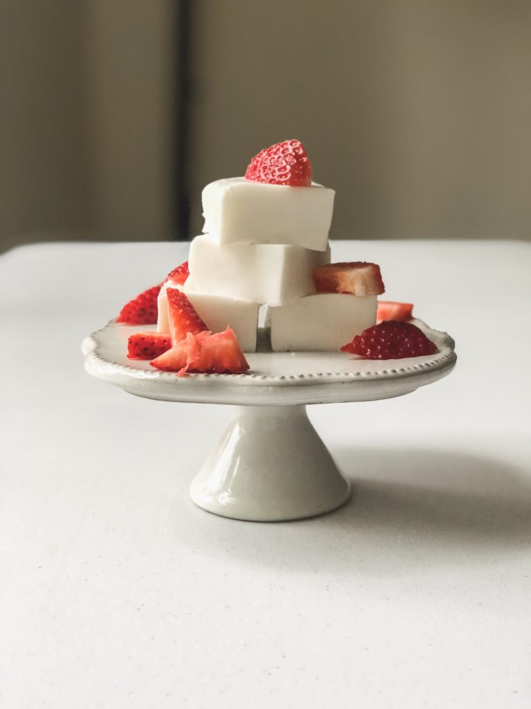 front view of haupia stacked in a pyramid on a stand with strawberries