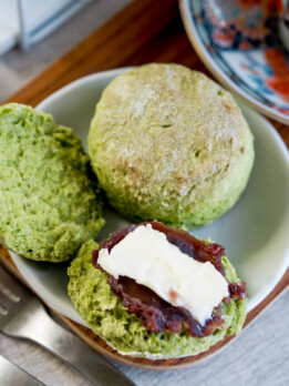 a round matcha scone split in half with a spread of red bean paste (anko) and a pat of butter on top