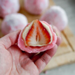 cross section of strawberry daifuku mochi with almond paste held in a hand